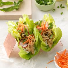 two lettuce wraps filled with meat and veggies next to a bowl of carrots