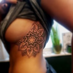 a woman's stomach with a tattoo on the side and an intricate flower design