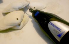 two small white birds sitting on top of a table next to a bottle of toothpaste