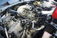 the engine compartment of a car with its hood up and hoses running through it