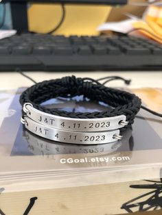 three bracelets with two names on them sitting on top of a table next to a keyboard