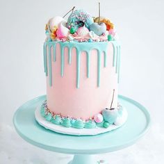 a pink and blue cake with icing drizzled on it's sides