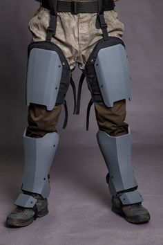 the legs and knees of a man in protective gear, standing with his hands on his hips