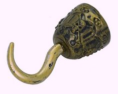 an old brass hook with a decorative design on it's end and a metal handle