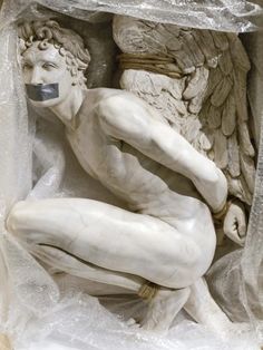 a white statue sitting inside of a wooden box on top of a floor next to a wall