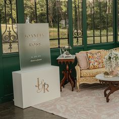 a living room filled with furniture and lots of green windows next to a white table