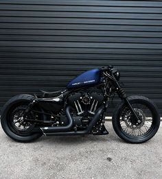 a black and blue motorcycle parked in front of a garage door