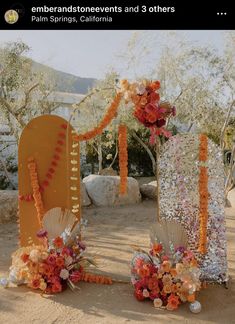 an outdoor wedding setup with orange and white flowers on the side, along with other decorations