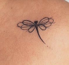 a small dragonfly tattoo on the back of a woman's upper back shoulder