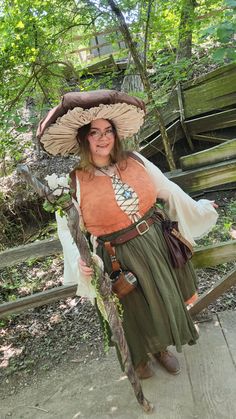 a woman wearing a hat and holding a stick in her hand while standing on a wooden walkway