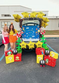 two women standing in front of a car decorated with mario and luigi's bows