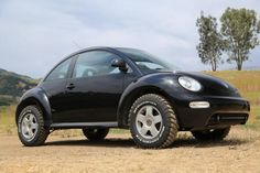 a small black car parked on top of a dirt road