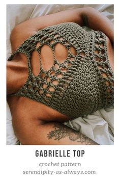 a woman laying in bed wearing a crochet top