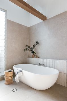 a large white bath tub sitting in a bathroom next to a wooden window sill