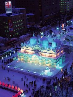 an aerial view of a building lit up in blue and white with people walking around it