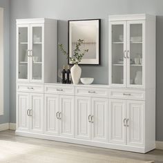 a white china cabinet with glass doors on the top and bottom, in front of a gray wall