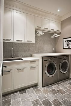 an image of a laundry room with washer and dryer on the floor in front of cabinets