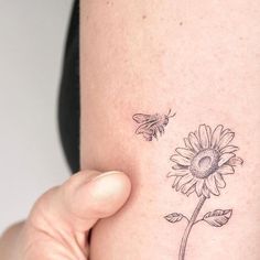 a woman's arm with a sunflower and a bee tattoo on the side