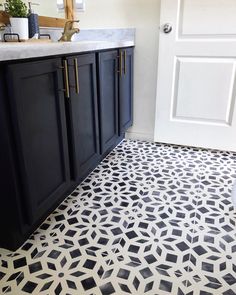 a bathroom with black and white tiles on the floor next to a door, sink and toilet