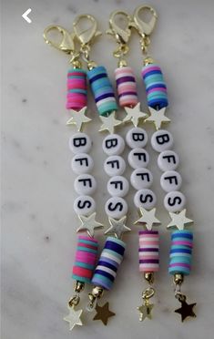 several bracelets with stars and letters are hanging on a marble countertop in front of a keychain