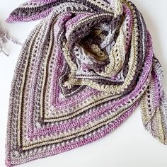 a multicolored crocheted scarf laying on top of a white table