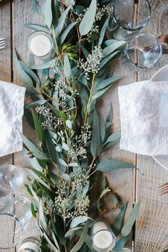 the table is set with candles and greenery