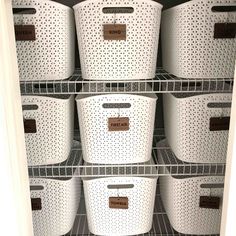 the closet is full of white baskets with brown labels on them, and there are several bins in it