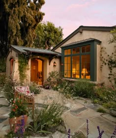 a house that is surrounded by plants and flowers