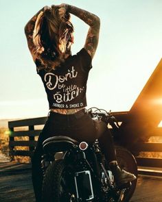 a woman sitting on top of a motorcycle with her hands behind her head and looking off to the side