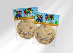 two chocolate chip cookies in plastic bags with game over stickers on them and an image of the same cookie