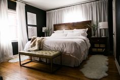 a bed with white sheets and pillows in a bedroom next to a wooden bench on a hard wood floor