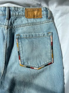 the back pocket of a pair of light blue jeans with an orange and yellow patch on it