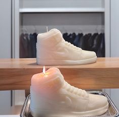 a pair of white sneakers sitting on top of a table next to a lit candle