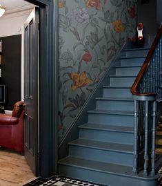 a living room filled with furniture and a stair case next to a wallpapered staircase