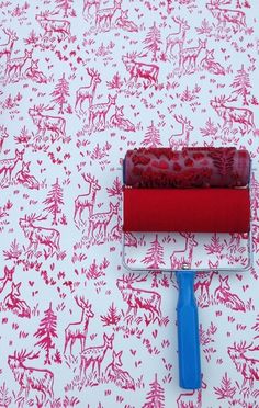 a red and white wallpaper with a paint roller on top of it next to a blue brush