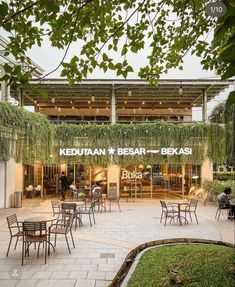 an outdoor restaurant with tables and chairs in front of the building that has plants growing on it