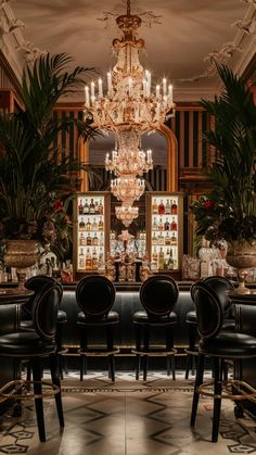 an elegant dining room with chandelier and black leather chairs in front of the bar