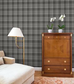 a living room with a couch, chair and lamp on the side table in front of a plaid wallpapered wall