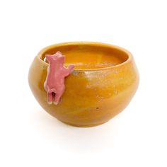 a yellow bowl with a pink pig on the side sitting in front of a white background