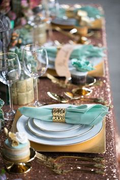 the table is set with gold, white and green plates and place settings for dinner