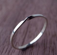 a close up of a silver ring on a wooden table with wood grained surface