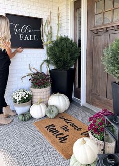 a woman standing in front of a door holding up a sign that says welcome fall