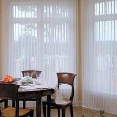 a dining room table and chairs in front of sheered windows