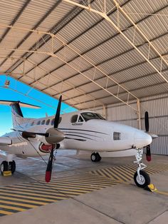 an airplane is parked in a hangar with yellow lines on the floor and blue sky behind it