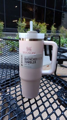 a pink coffee cup sitting on top of a metal table