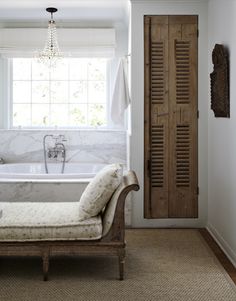 a bath room with a tub a chair and a window