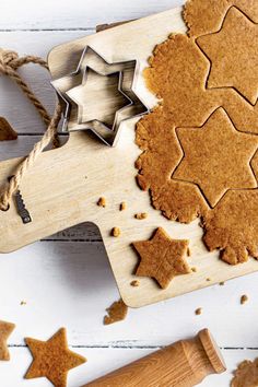 some cookies are on a cutting board with star shaped cookie cutters next to them