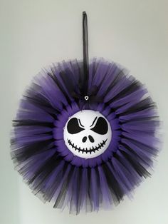 a purple and black tutu skirt with a skeleton face on the front is hanging from a hook