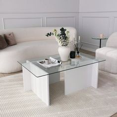 a living room with two white couches and a glass coffee table in the middle