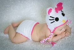 a baby wearing a hello kitty hat and diaper laying on top of a white blanket